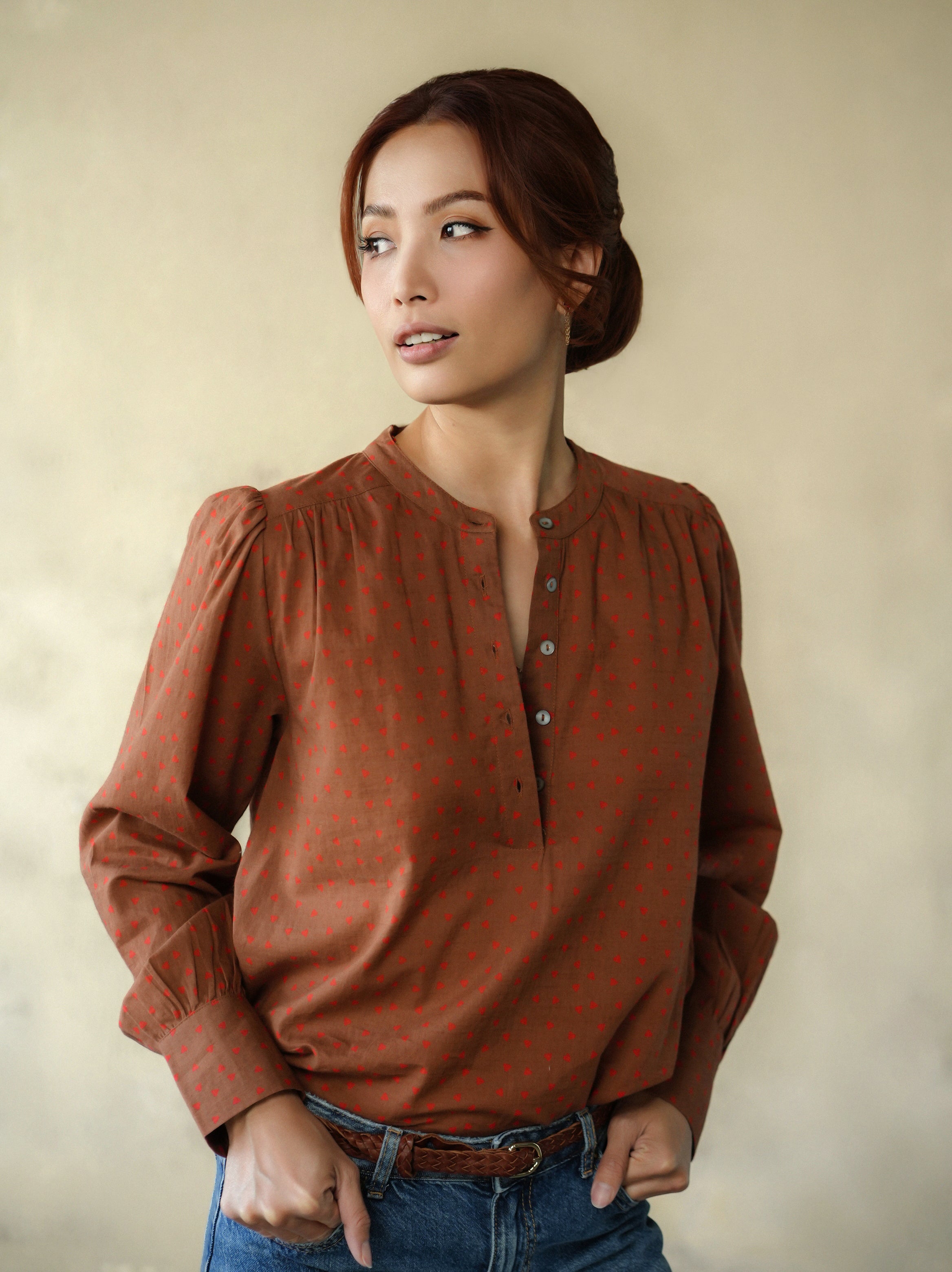 Woman wearing a brown blouse against a beige background